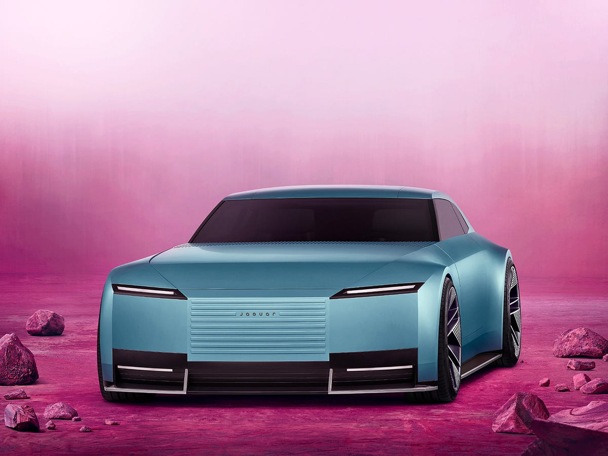 Une voiture concept Jaguar Type 00, avec des lignes futuristes et une carrosserie brillante, présentée dans un environnement minimaliste et high-tech.