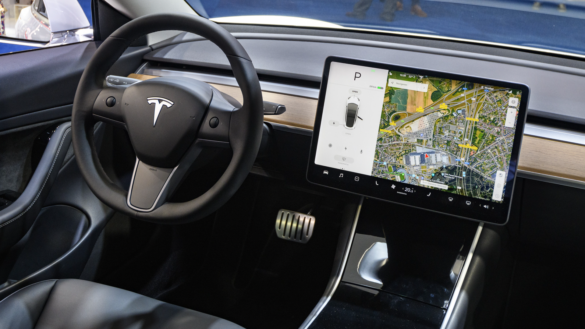 Intérieur d'une Tesla avec le système Autopilot activé, montrant le volant et le tableau de bord, suggérant une conduite autonome sur une route française.