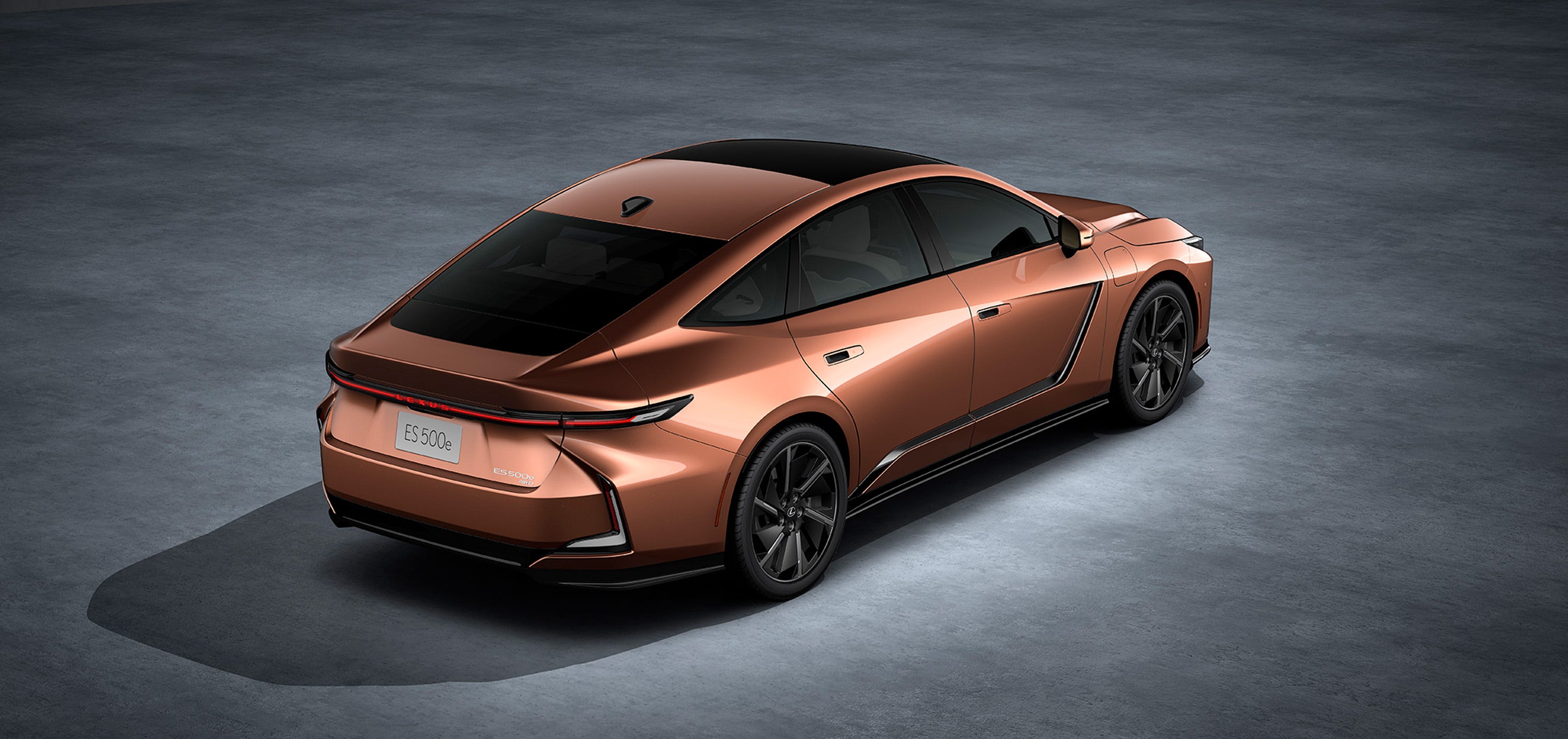 Vue extérieure d'une Lexus ES 2026 grise, garée en ville au crépuscule, avec ses phares allumés.