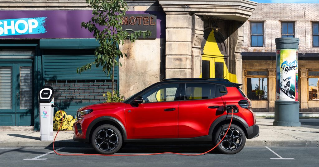 Une Citroën ë-C3 blanche est branchée à une borne de recharge rapide dans un environnement urbain.