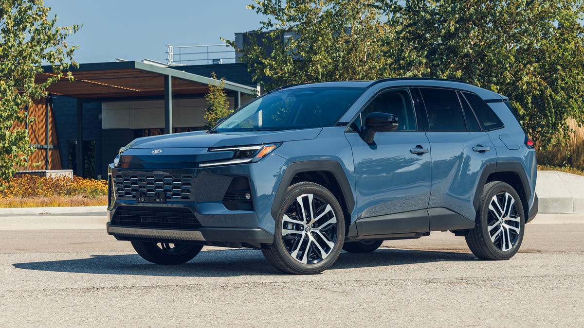 Un Toyota RAV4 2026 de couleur sombre, garé en pleine nature, avec des montagnes en arrière-plan.