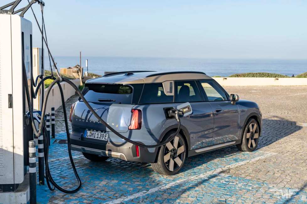 Une Mini Cooper Electric 2024 branchée à une borne de recharge publique dans une rue pavée européenne.