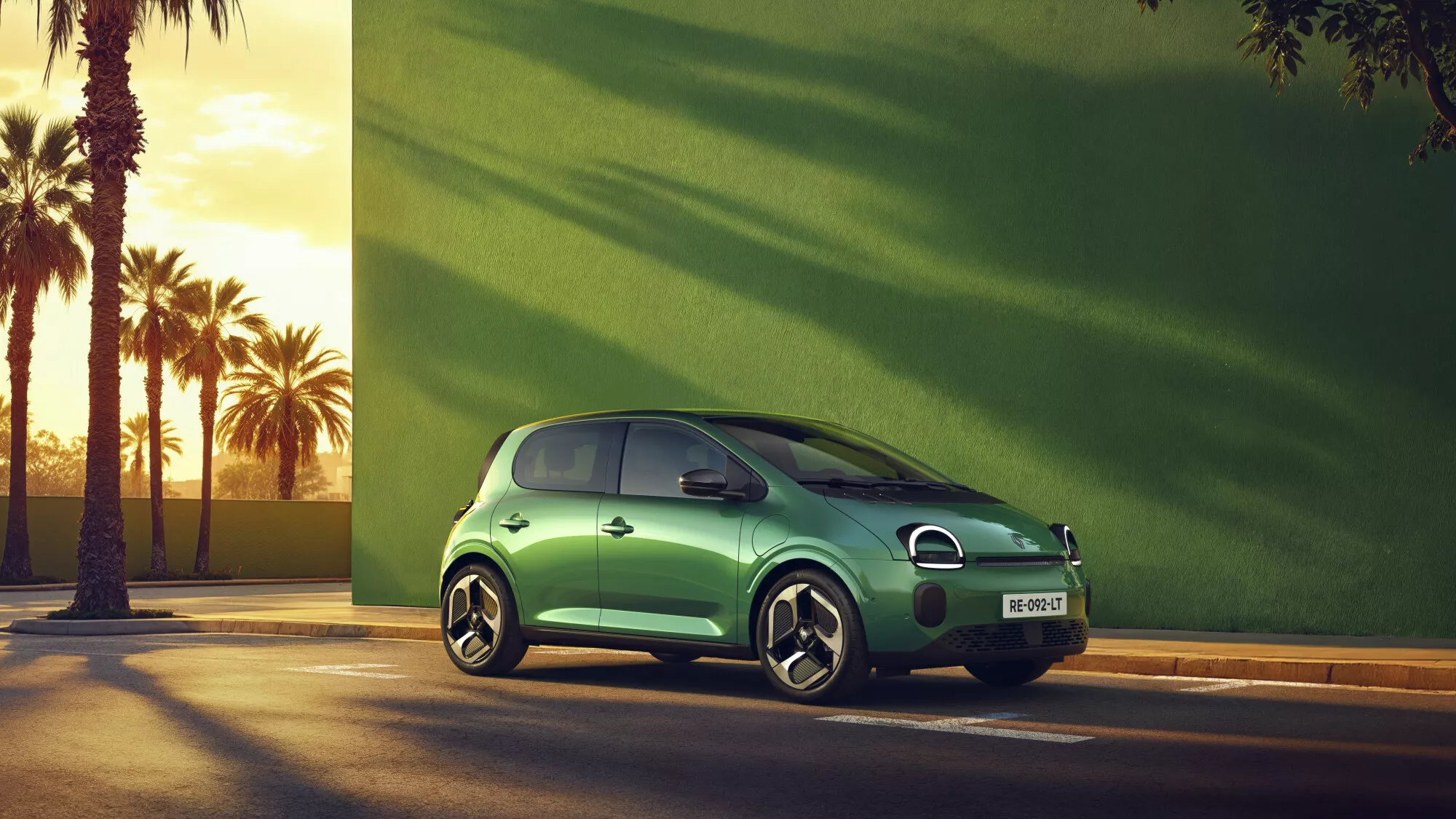 Une Renault Twingo E-Tech électrique de couleur vive circulant dans une rue urbaine animée, avec des bâtiments modernes en arrière-plan.