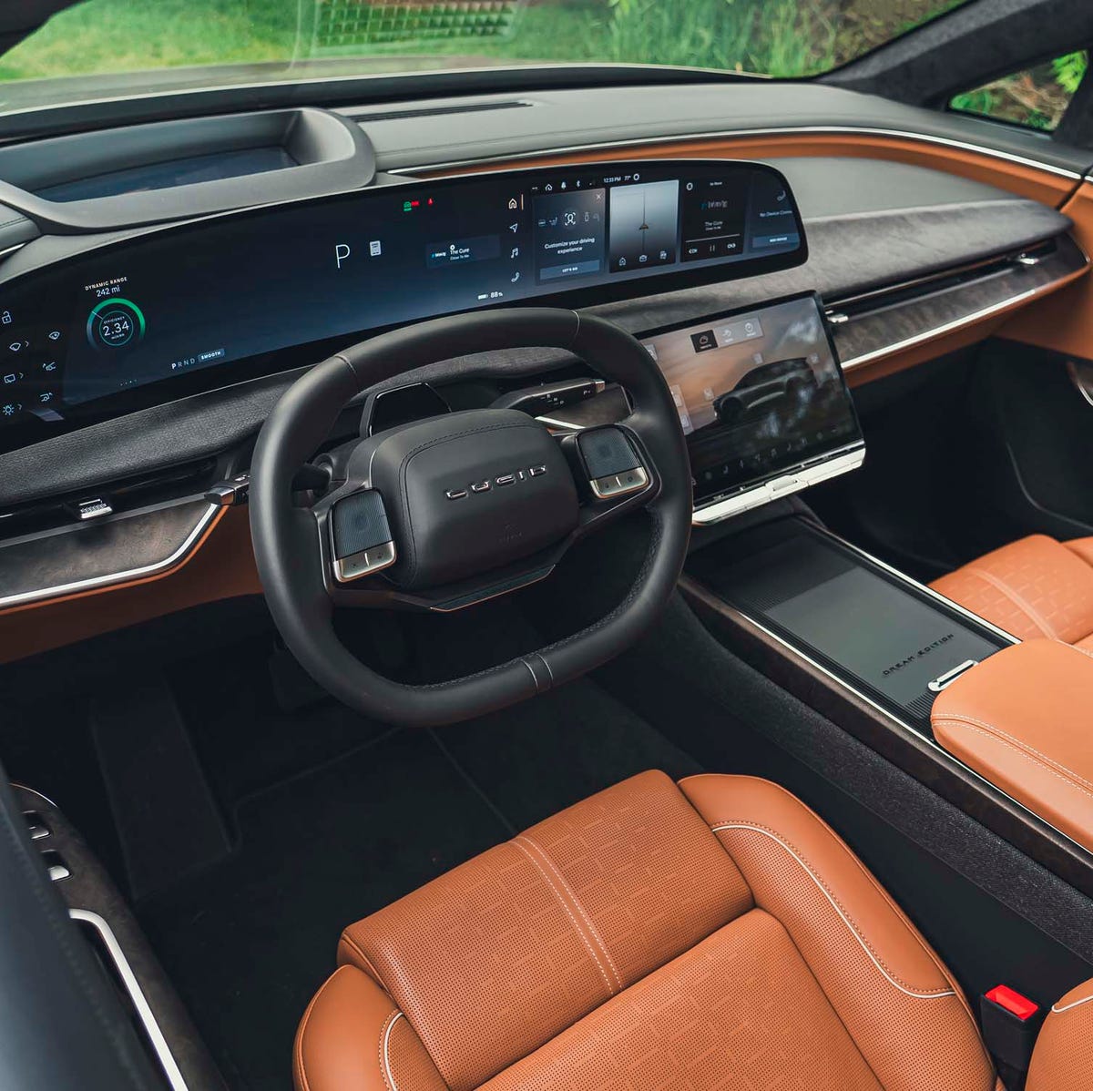 Vue intérieure d'une Lucid Air, mettant en valeur le tableau de bord avec son grand écran incurvé, les sièges en cuir et les finitions luxueuses.
