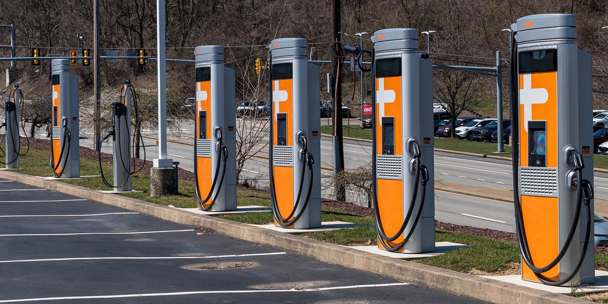 Une voiture électrique branchée à une borne de recharge dans une rue de ville animée.