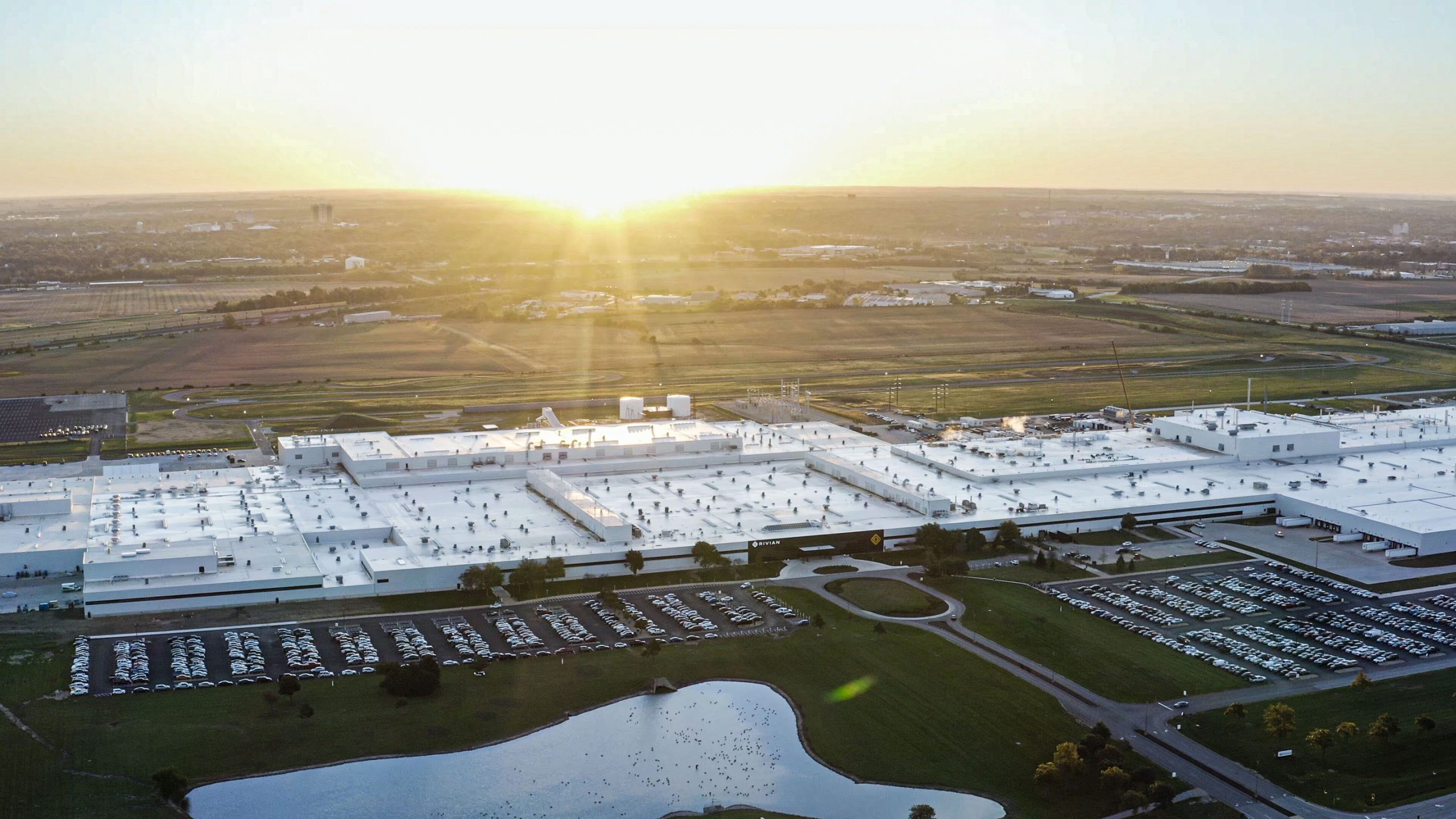 Vue extérieure de l'immense usine Rivian à Normal, Illinois, avec des panneaux solaires visibles sur le toit.