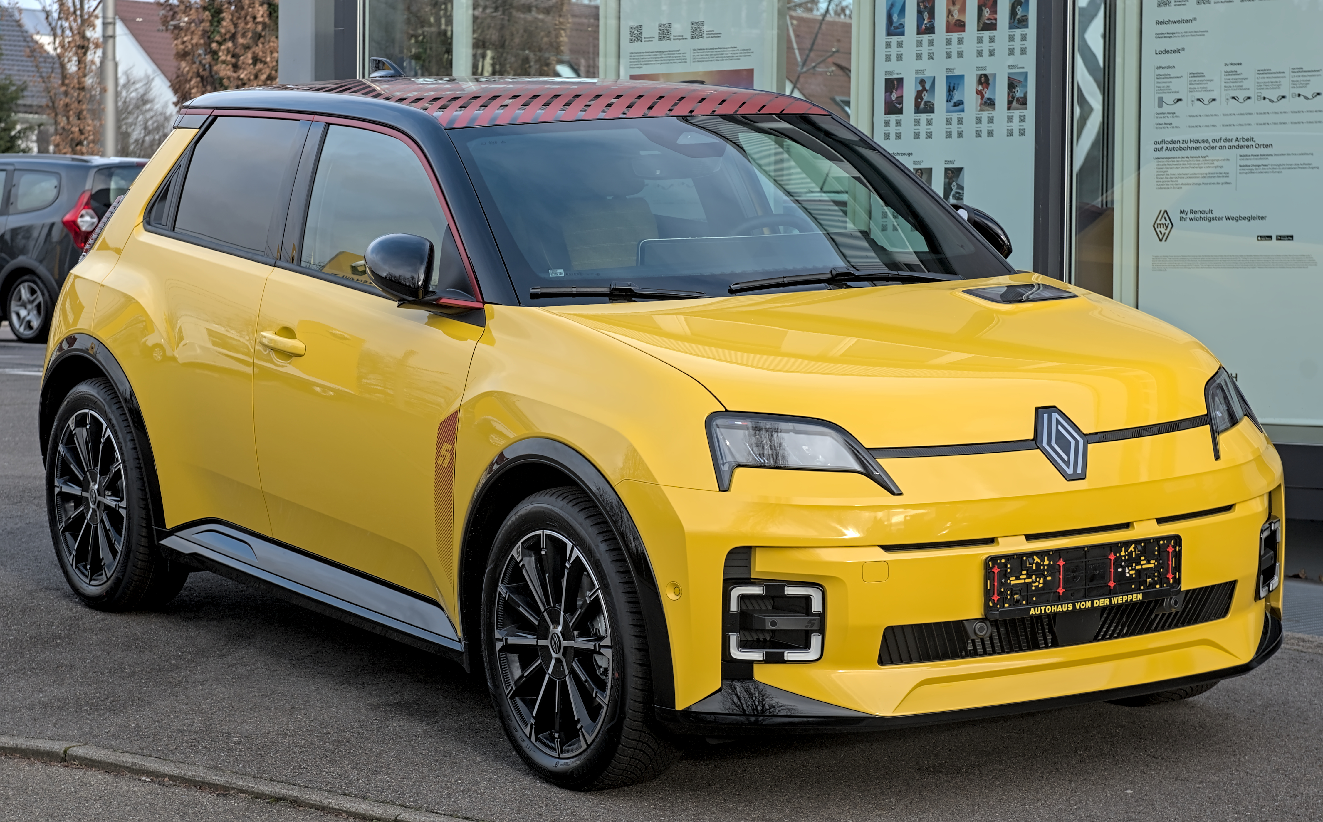 Une Renault 5 E-Tech électrique en mouvement sur une route de ville moderne, mettant en valeur son design néo-rétro.