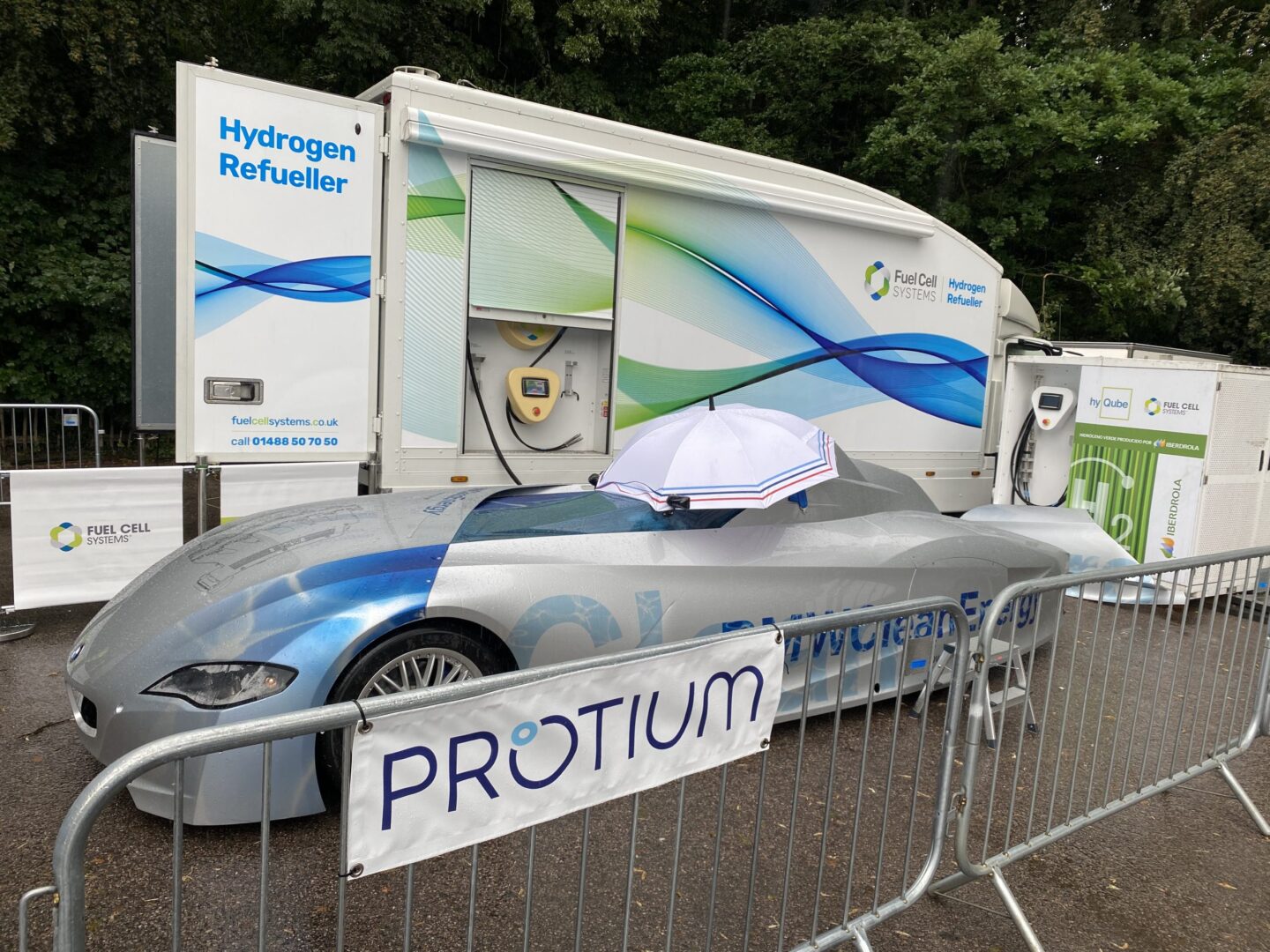 Image d'une station de ravitaillement en hydrogène pour voitures de course, montrant des tuyaux sous haute pression et des techniciens en équipement de protection.