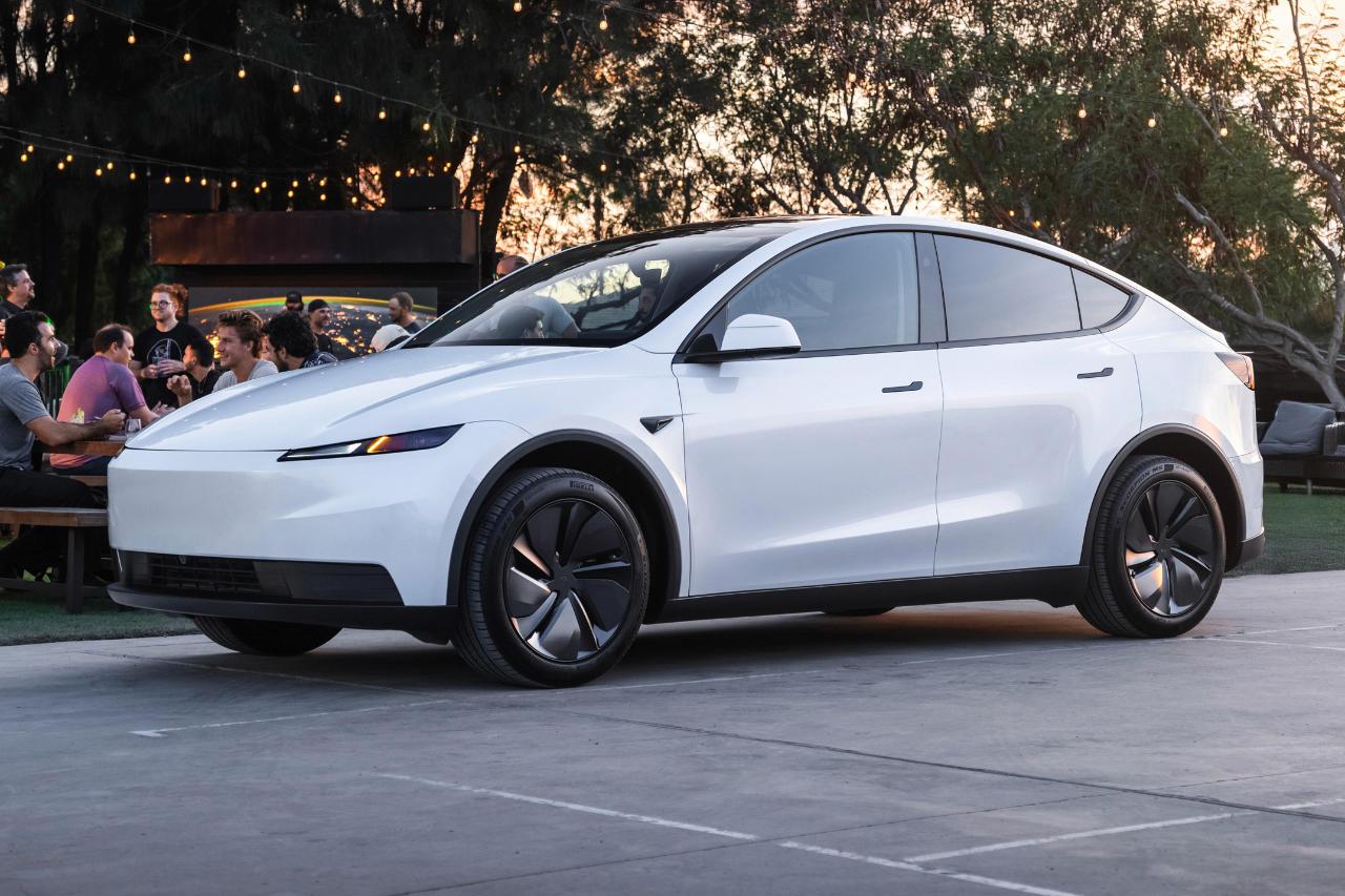 Un Tesla Model Y Propulsion blanc roulant sur une route de campagne française ensoleillée.