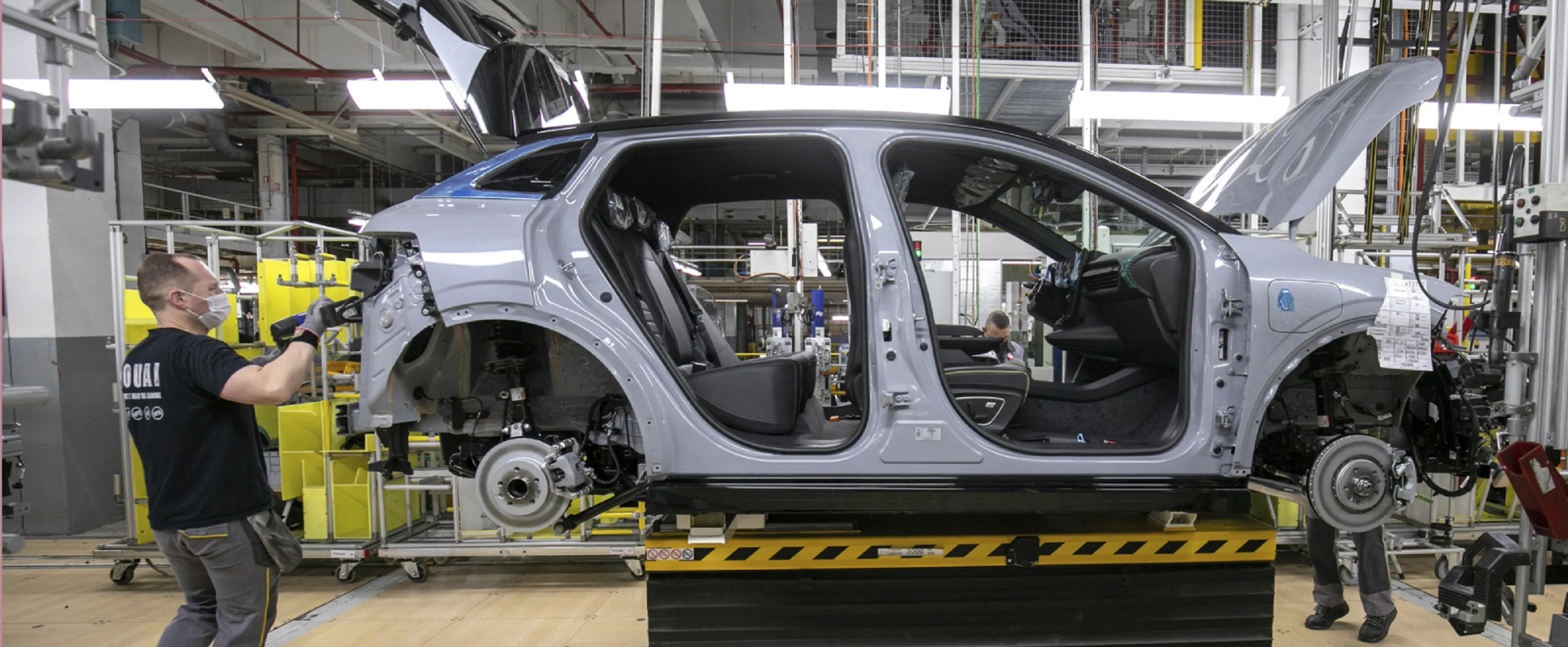 Des robots et des ouvriers qualifiés travaillent sur une chaîne de production de voitures électriques dans une usine française de pointe.