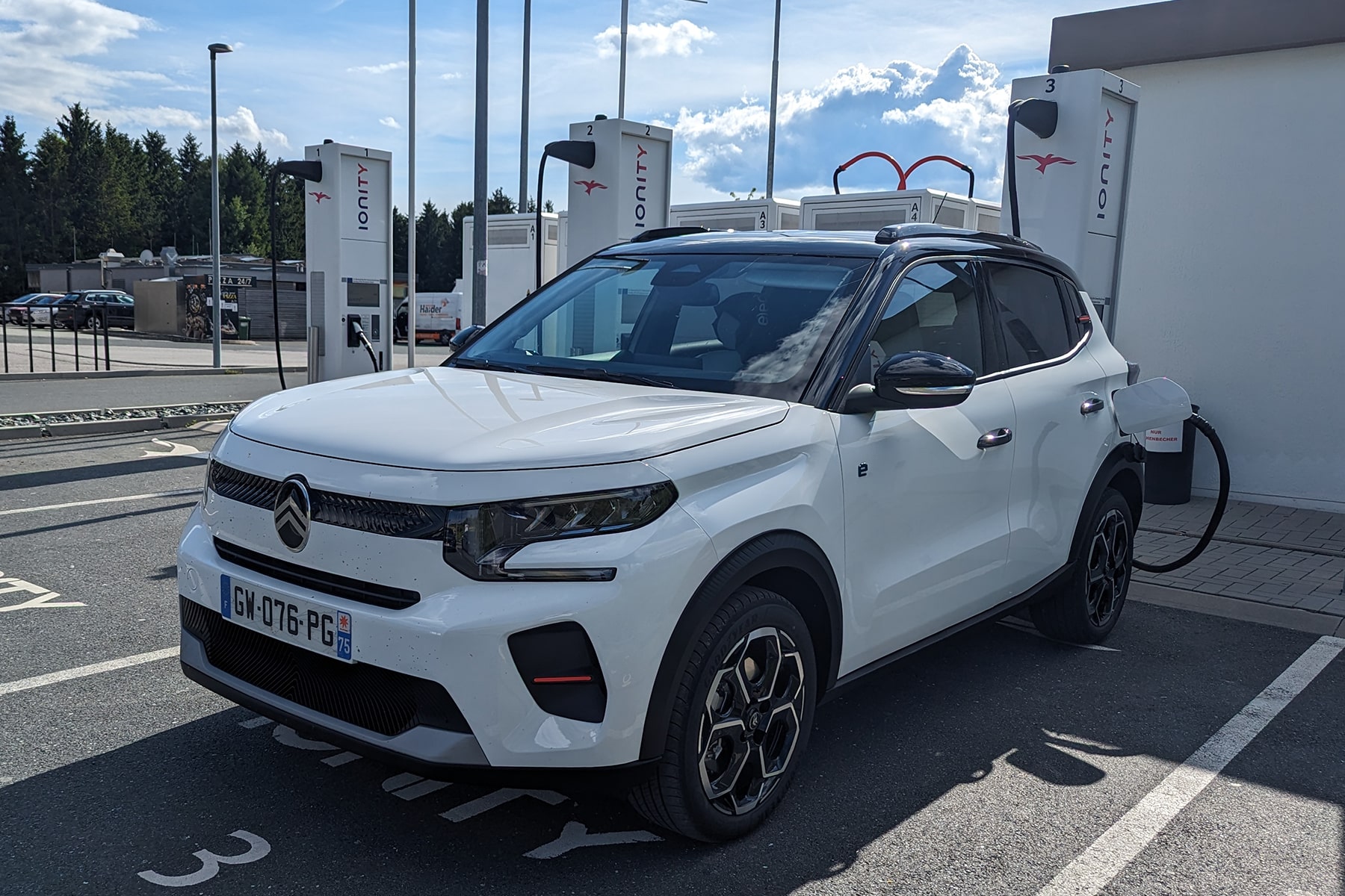 Une voiture électrique moderne en charge dans une ville française, avec des graphiques financiers superposés symbolisant les subventions.