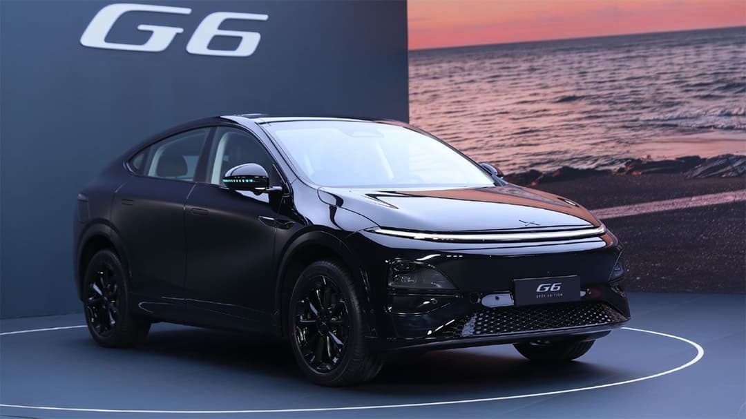 Vue latérale d'un Xpeng G6 2026 blanc, mettant en valeur ses lignes épurées, ses phares fins et ses jantes aérodynamiques, garé dans un environnement urbain moderne.