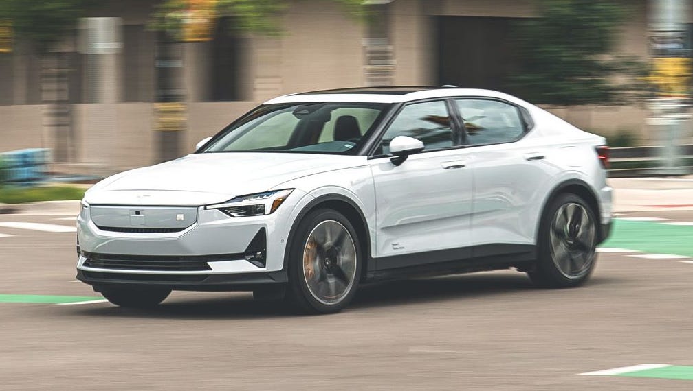 Une Polestar 2 blanche roulant sur une autoroute américaine, avec des gratte-ciel en arrière-plan.