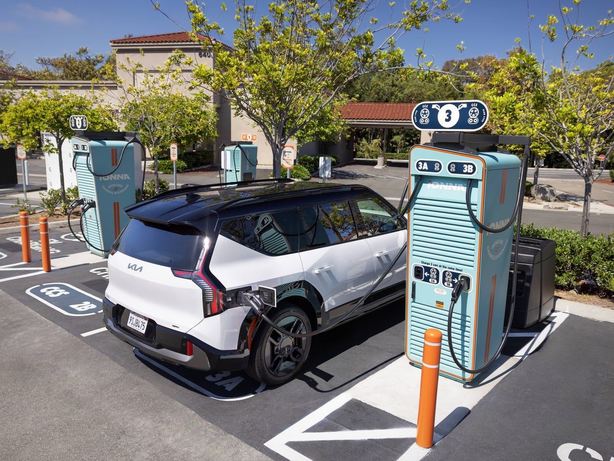 Image d'une voiture électrique en charge sur une borne publique moderne dans un environnement urbain futuriste.