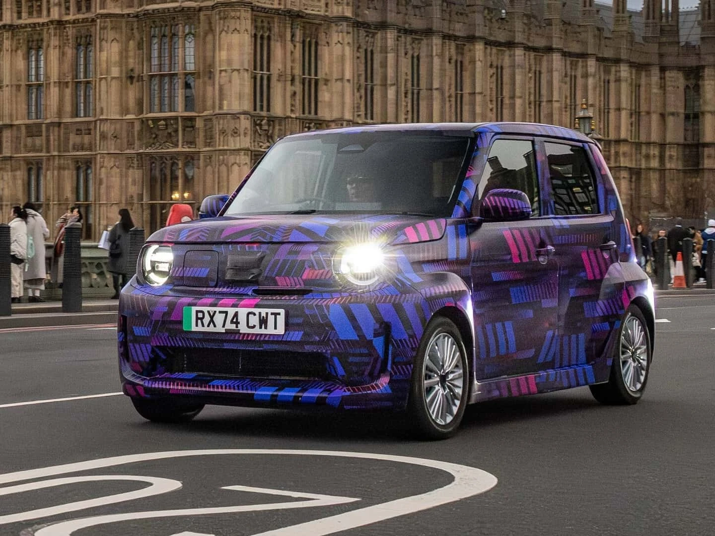 Une Honda Super-N électrique compacte et moderne, garée dans une rue de ville, avec des bâtiments en arrière-plan.