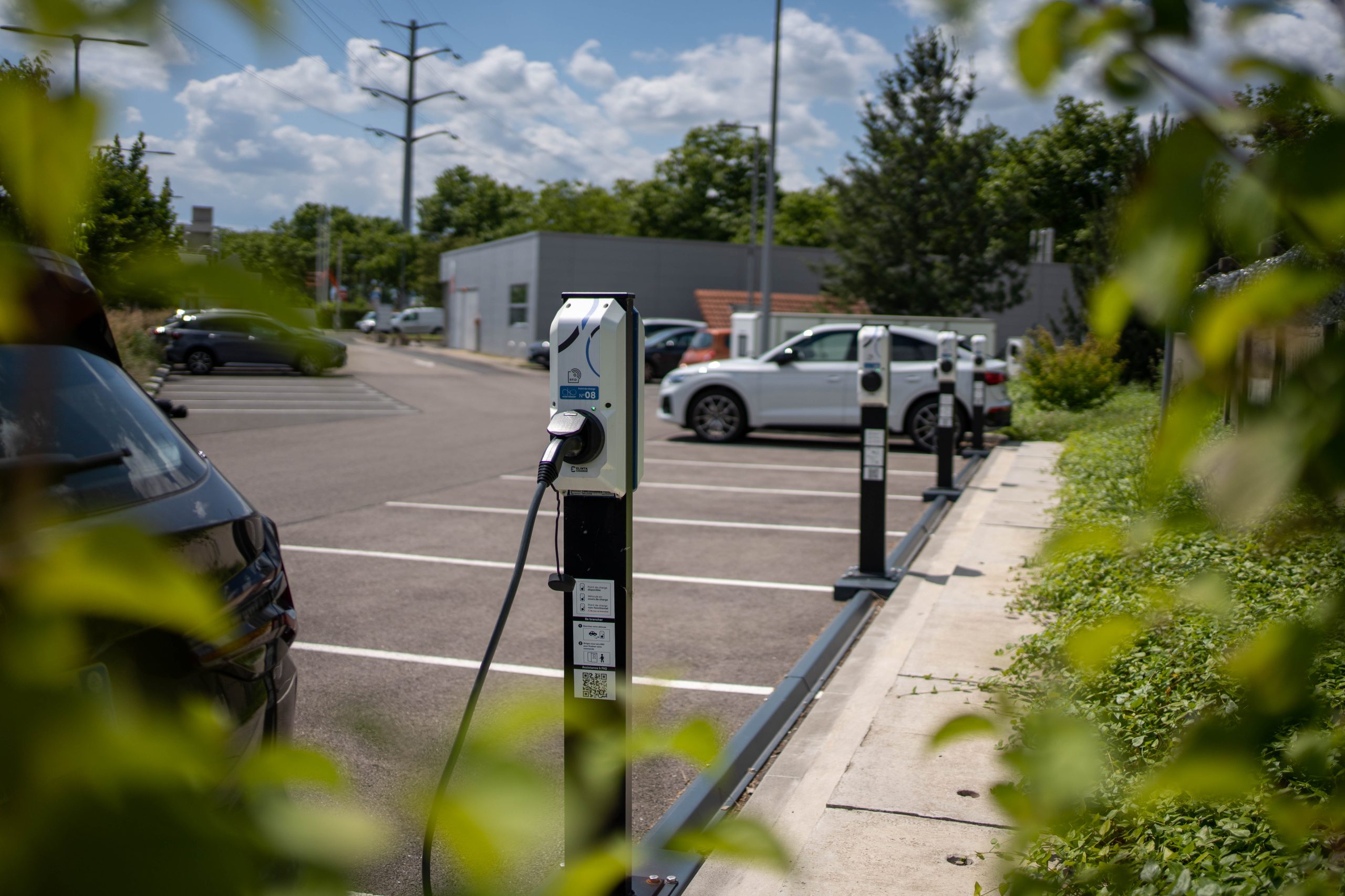 Une voiture électrique grise branchée à une borne de recharge dans un parking souterrain moderne et éclairé d'un immeuble résidentiel.