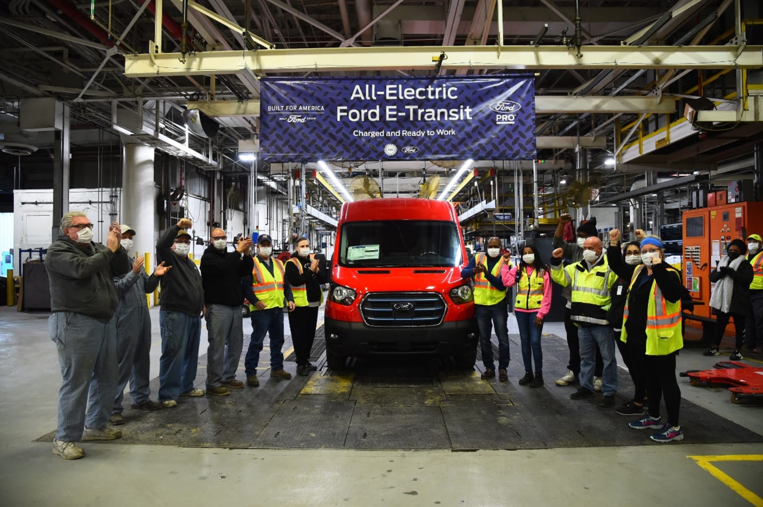 Image d'un Ford Transit électrique sur une chaîne de montage, avec des robots et des ouvriers, illustrant la fabrication du véhicule.