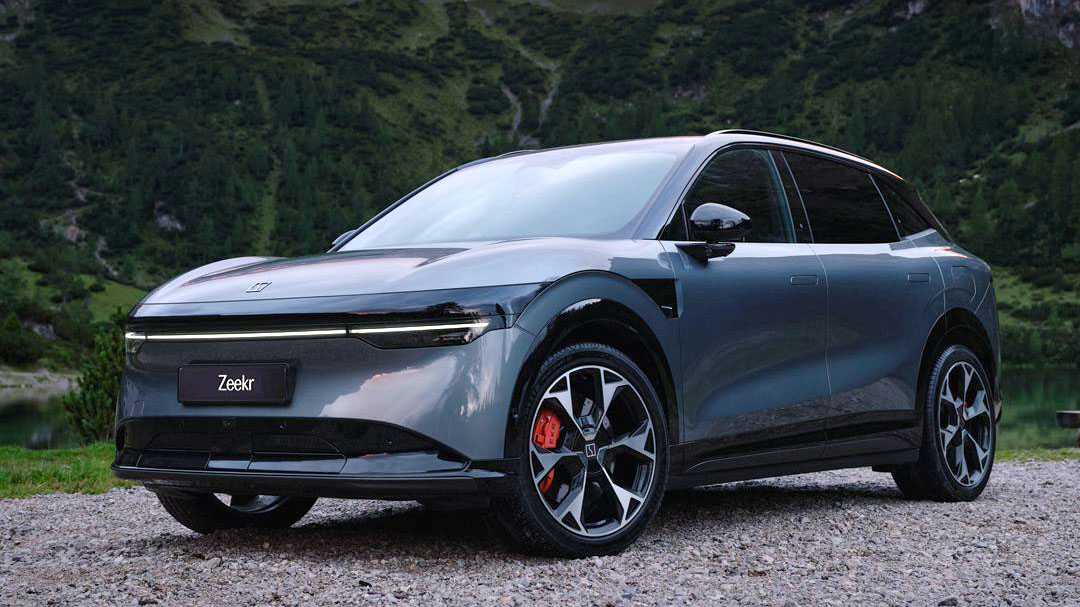 Un SUV électrique Zeekr 001 de couleur sombre, en mouvement sur une route sinueuse en Italie, avec des bâtiments anciens en arrière-plan.