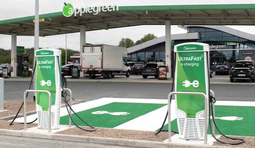 Une station de recharge rapide pour véhicules électriques sur une aire d'autoroute, avec plusieurs voitures en train de charger.