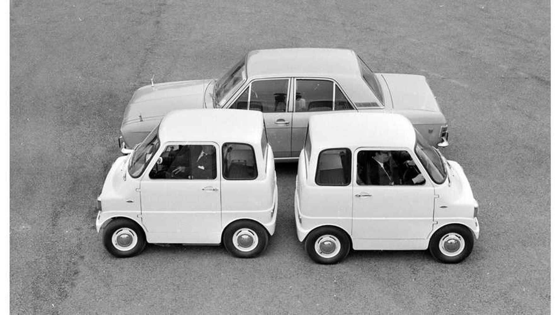 Image d'un prototype camouflé du véhicule électrique Ford à 30 000 $ en cours d'essai sur une piste, avec des ingénieurs en arrière-plan.