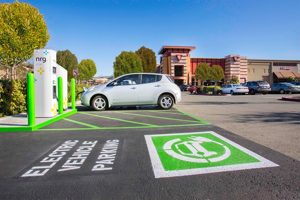 Un procès-verbal sur le pare-brise d'une voiture électrique garée illégalement sur une place de recharge.