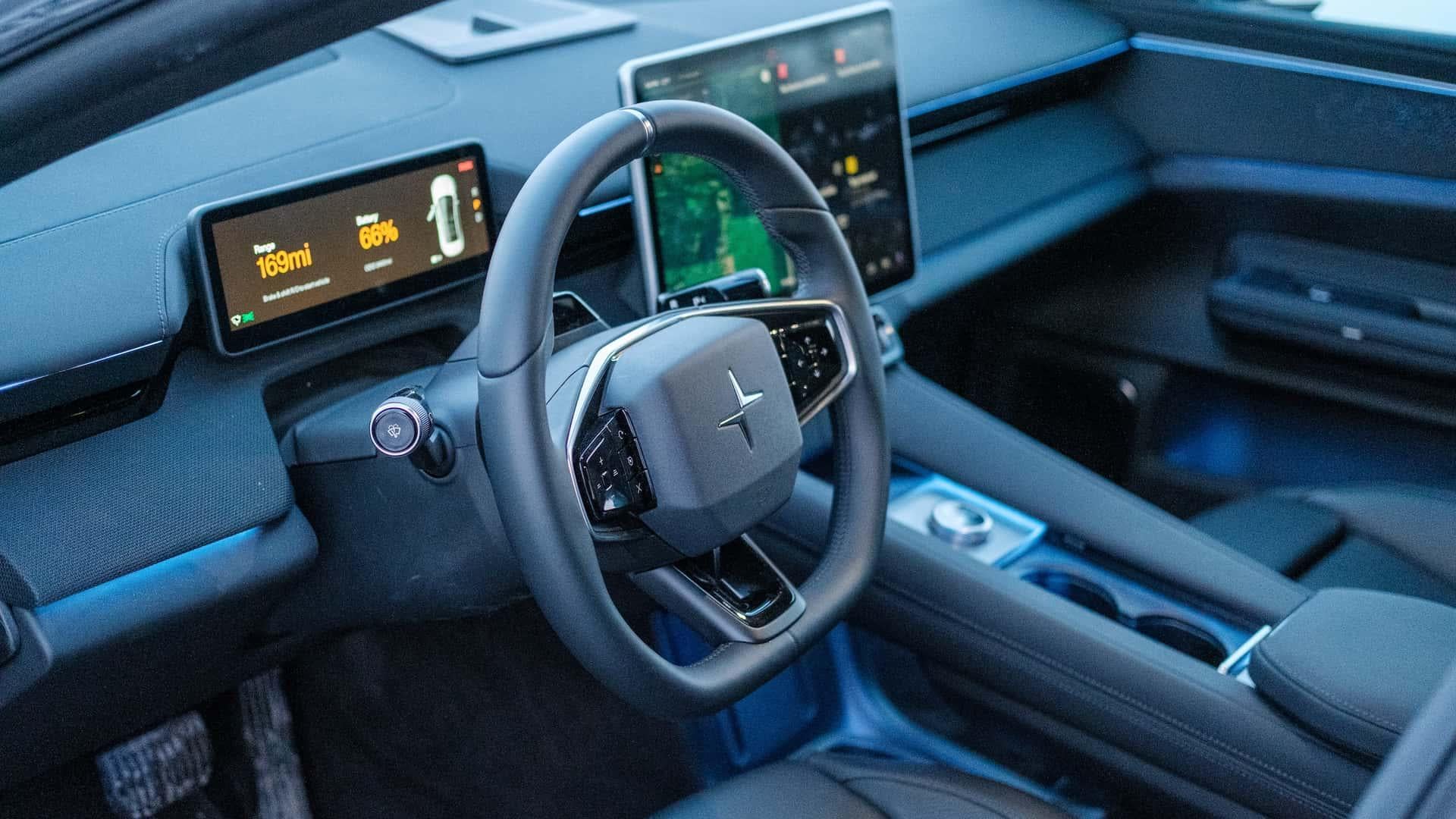 Vue de l'intérieur d'une voiture Polestar, montrant un tableau de bord moderne avec un grand écran tactile central et des boutons physiques bien intégrés pour les fonctions essentielles.