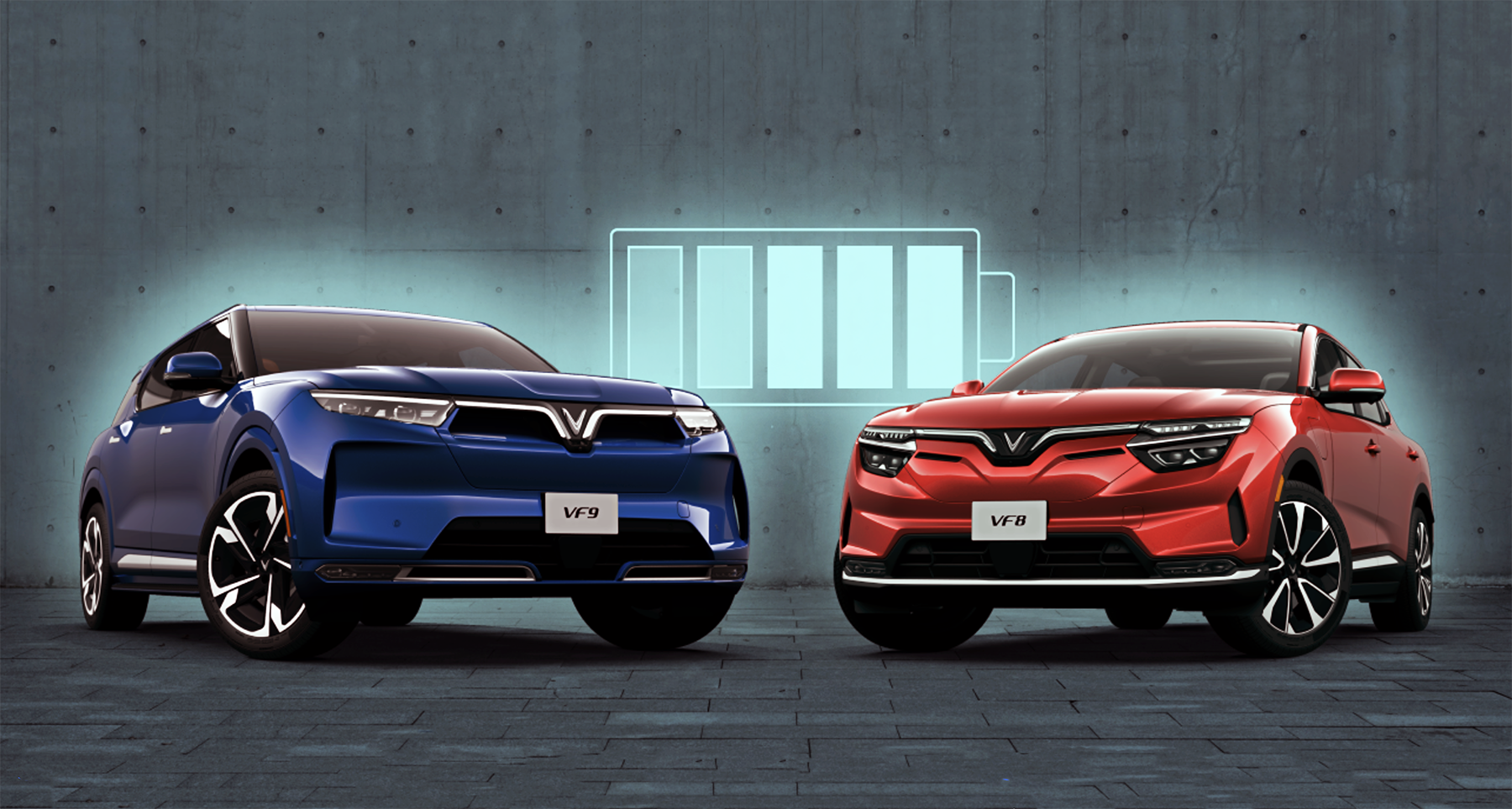 Deux SUV électriques, un VinFast VF 8 et un VinFast VF 9, roulant sur une autoroute avec une ville en arrière-plan.