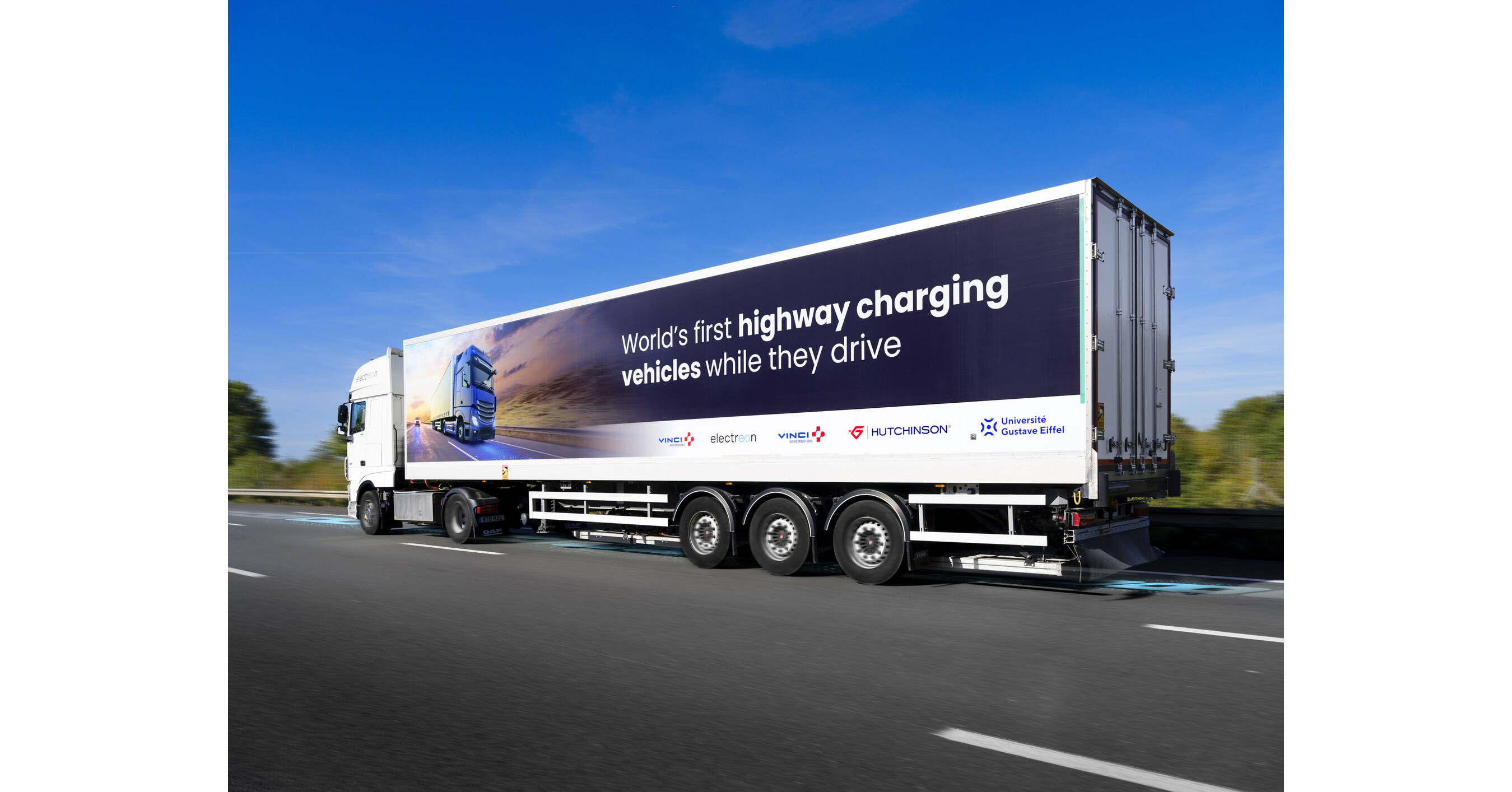 Des camions semi-remorques électriques roulant sur une autoroute, avec des paysages verdoyants en arrière-plan.