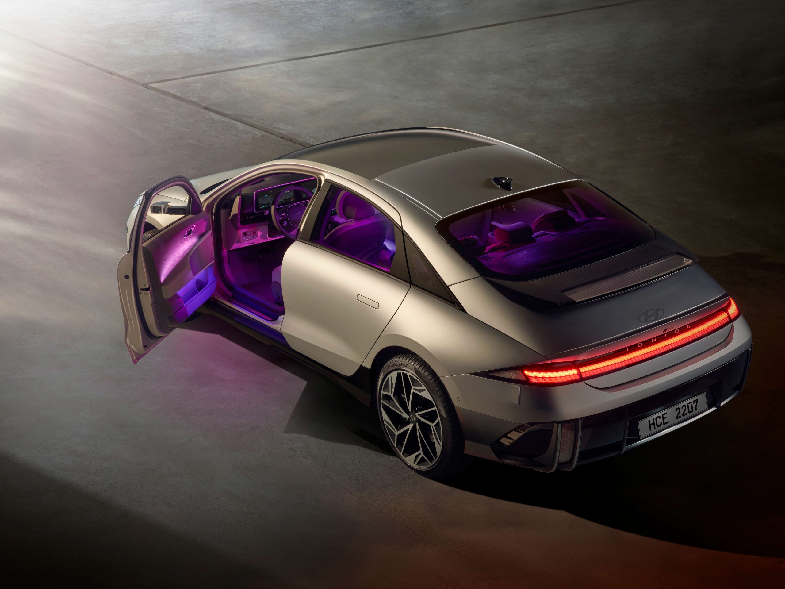 Un gros plan dynamique de la Hyundai Ioniq 6, mettant en évidence son design futuriste et aérodynamique, en mouvement sur une autoroute avec des lumières de ville floues en arrière-plan.