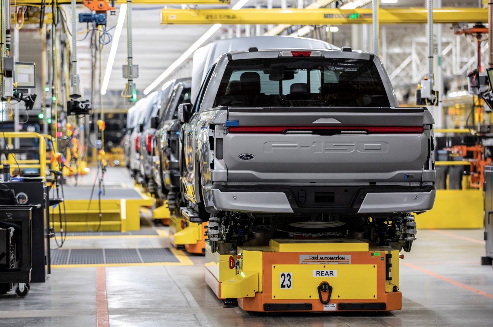 Une scène de fabrication en usine montrant un bras robotique géant versant du métal en fusion dans un moule pour créer le châssis d'un pickup électrique Ford.