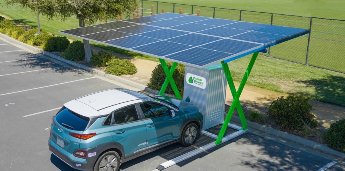 Borne de recharge intelligente avec compteur et panneaux solaires sur le toit d'un immeuble.