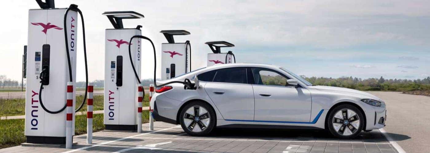 Plusieurs voitures électriques BMW, dont un iX3, se rechargent à une station de recharge futuriste.
