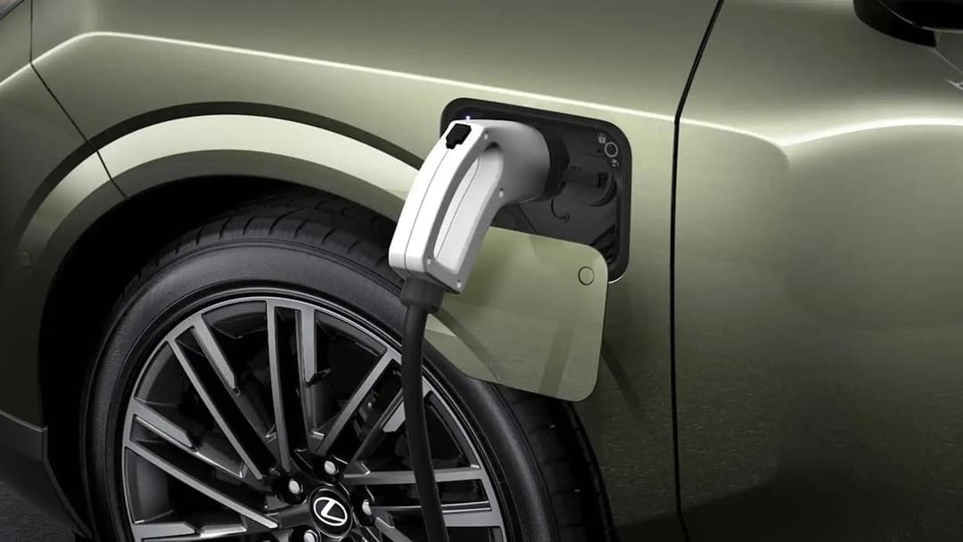 Un Lexus TZ blanc branché à une borne de recharge rapide, avec un câble de charge visible.