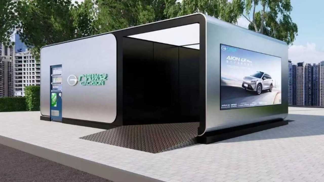 Une voiture électrique Aion RT Super dans une station d'échange de batterie futuriste, avec des bras robotiques remplaçant la batterie.