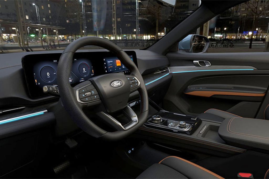 Vue extérieure du Ford Territory Hybride 2026 de couleur foncée, garé sur une route sinueuse avec des montagnes en arrière-plan au Maroc, mettant en valeur son design robuste.