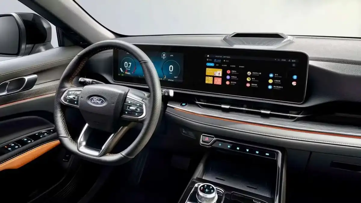 Intérieur du Ford Territory Hybride 2026 montrant le tableau de bord avec deux grands écrans, des sièges en cuir et des finitions métalliques, suggérant un environnement moderne et confortable.