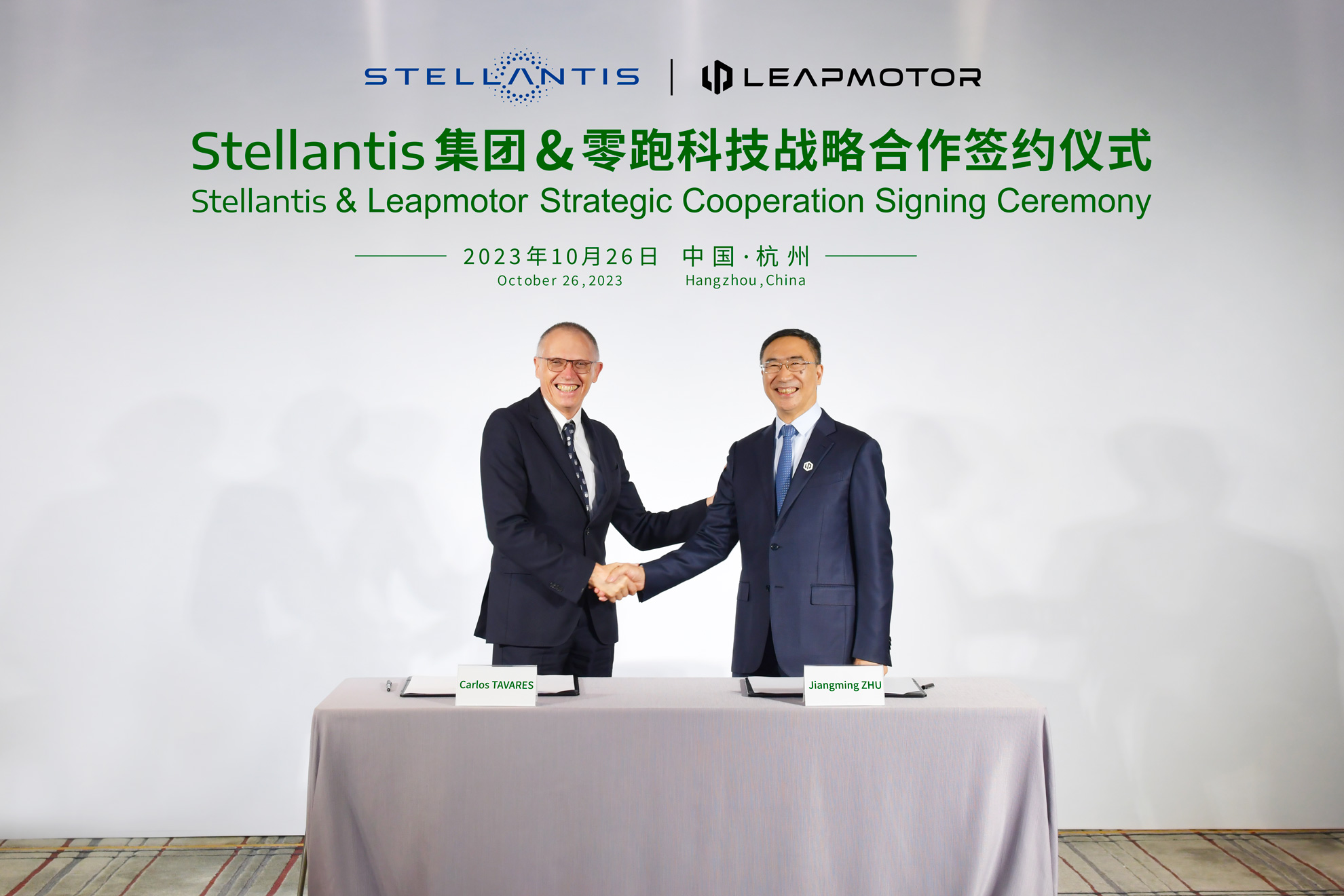 Deux dirigeants, l'un de Leapmotor et l'autre de Stellantis, se serrent la main lors d'une cérémonie de signature, symbolisant leur alliance.