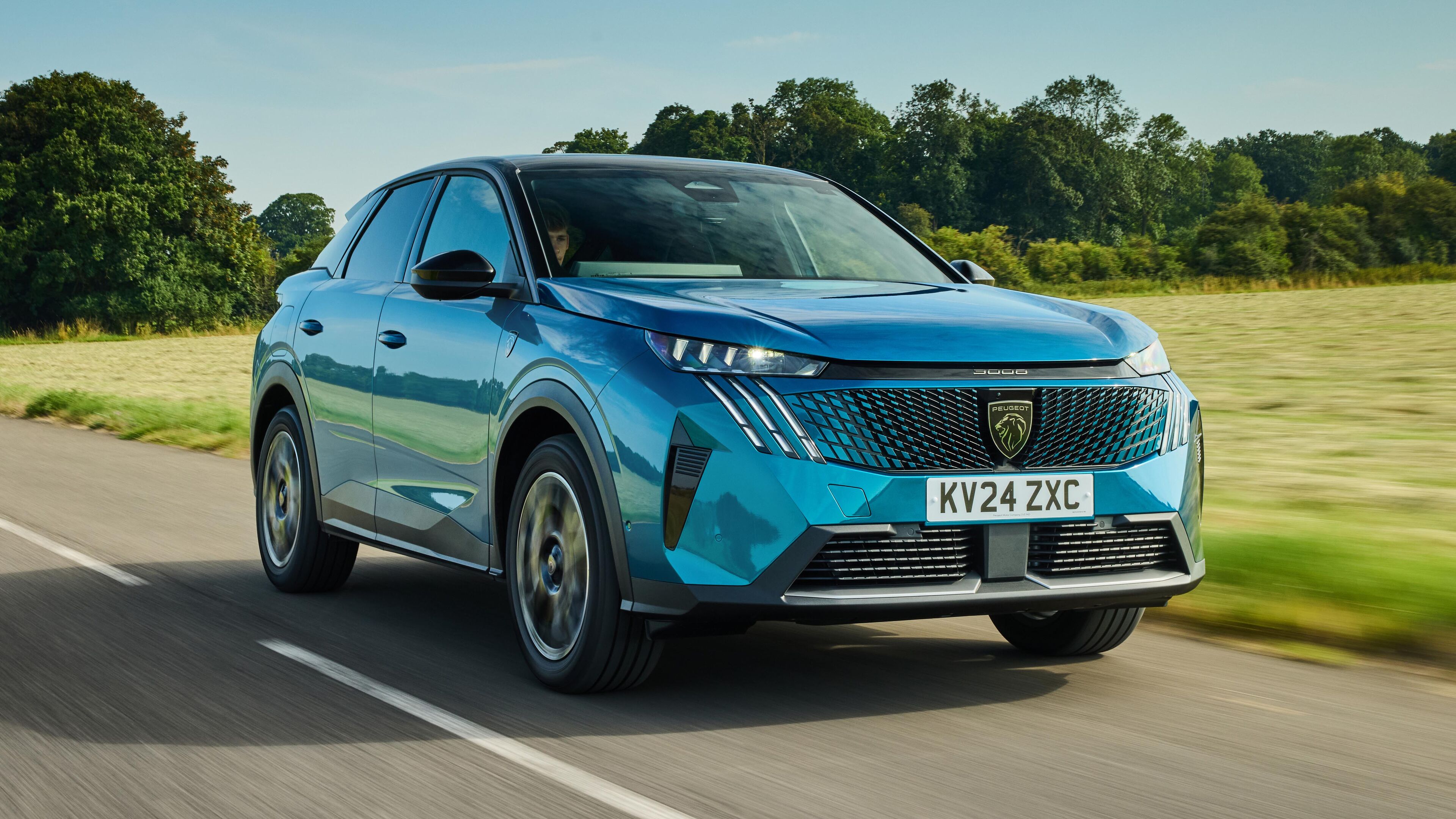 Une Peugeot 3008 Hybride 2026 grise circulant dans une rue de ville moderne, avec des bâtiments en arrière-plan.