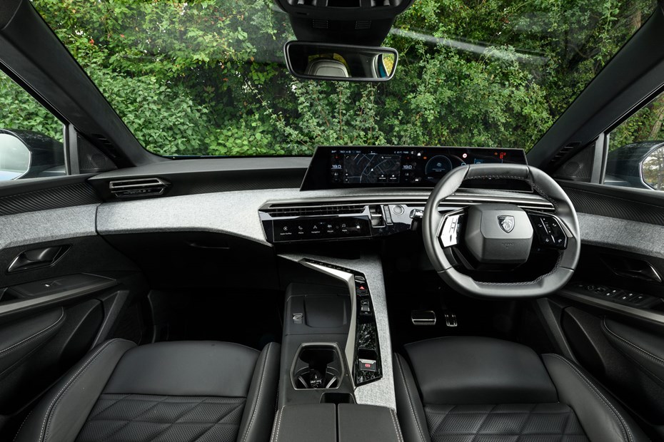 Vue de l'intérieur d'une Peugeot 3008 Hybride 2026, montrant le tableau de bord numérique, l'écran tactile central et le volant.