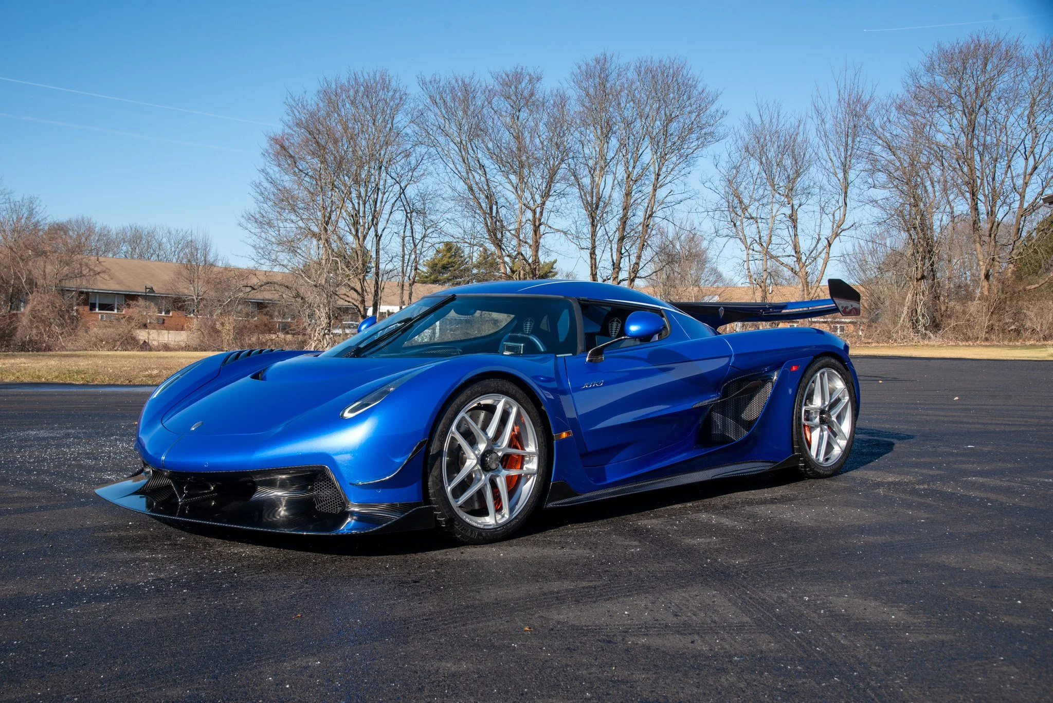 Une Koenigsegg Jesko Attack bleue en fibre de carbone, garée dans un showroom moderne.