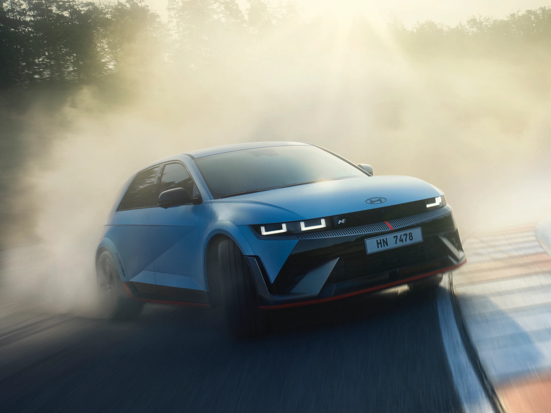 Une Hyundai Ioniq 5 N rouge et noire en train de drifter sur une piste de course, avec de la fumée s'échappant des pneus arrière.