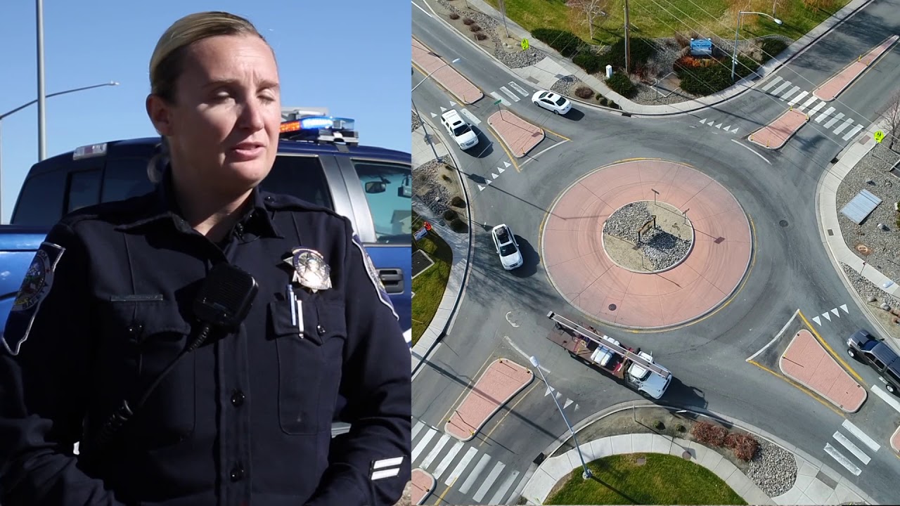 Des policiers en uniforme patrouillent près d'un rond-point animé, surveillant la circulation et les piétons.