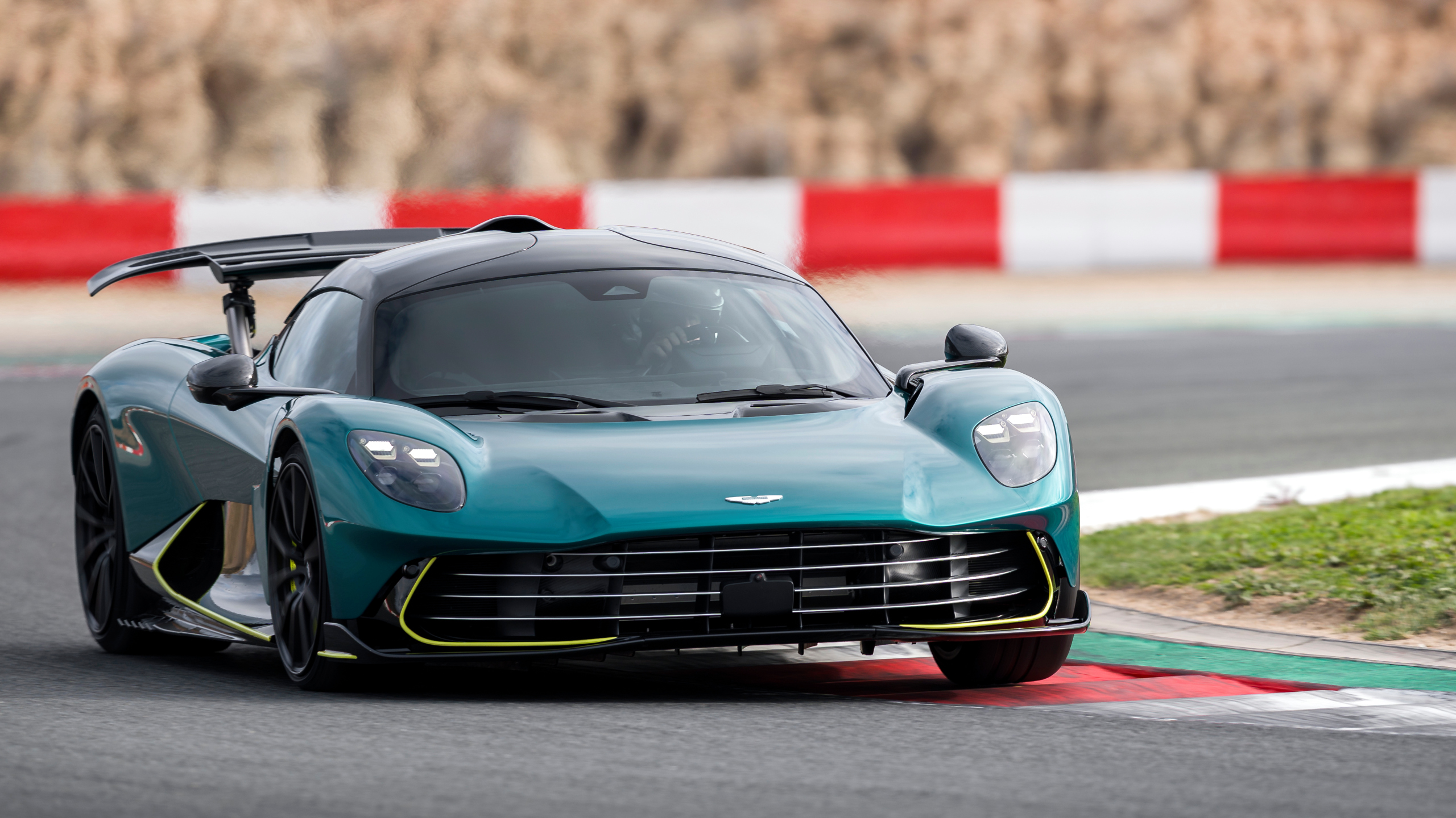 Une Aston Martin Valhalla rouge en train de drifter sur une piste de course, avec de la fumée s'échappant des pneus arrière.