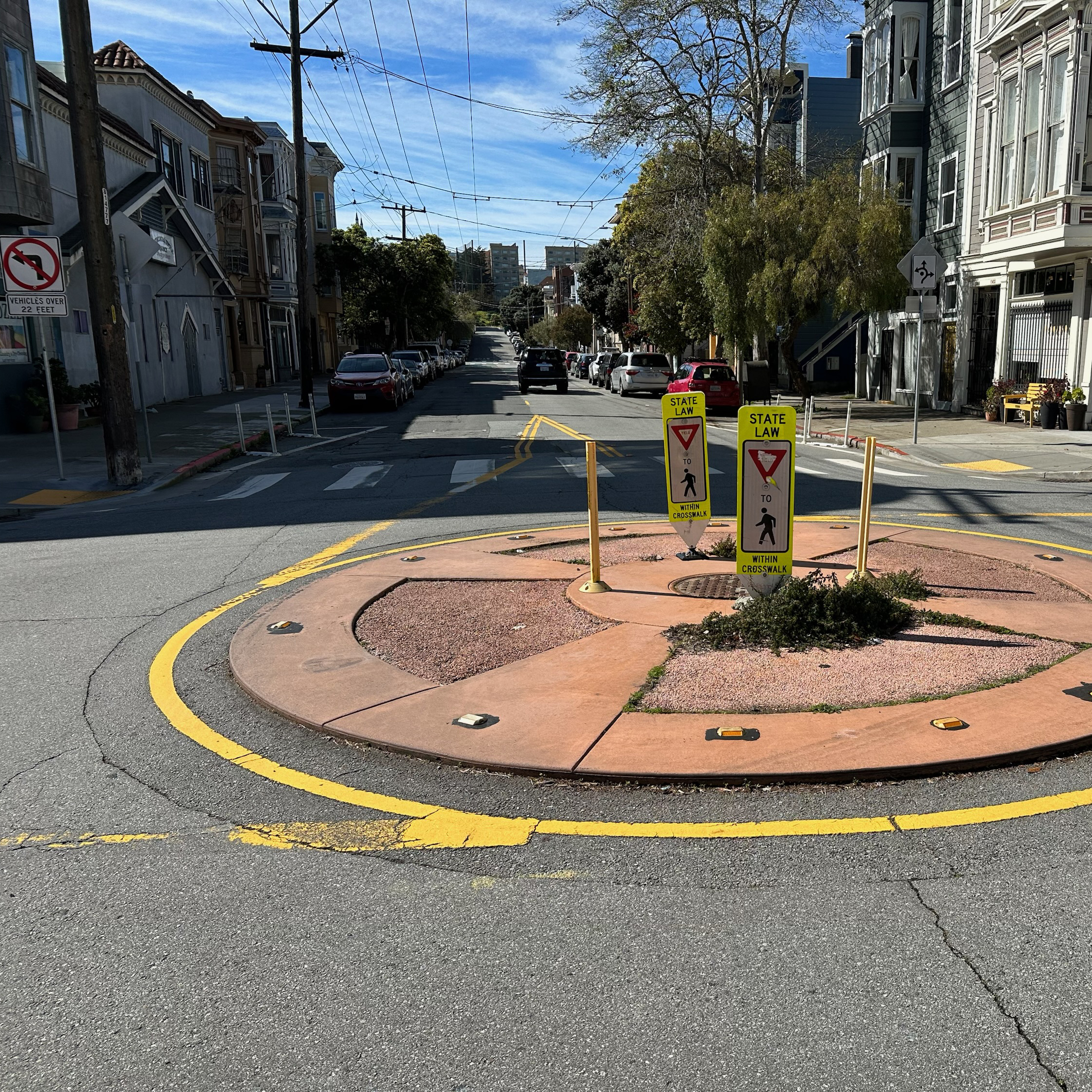 Vue aérienne d'un rond-point dont l'îlot central est endommagé, avec des bordures cassées et des plantations arrachées.
