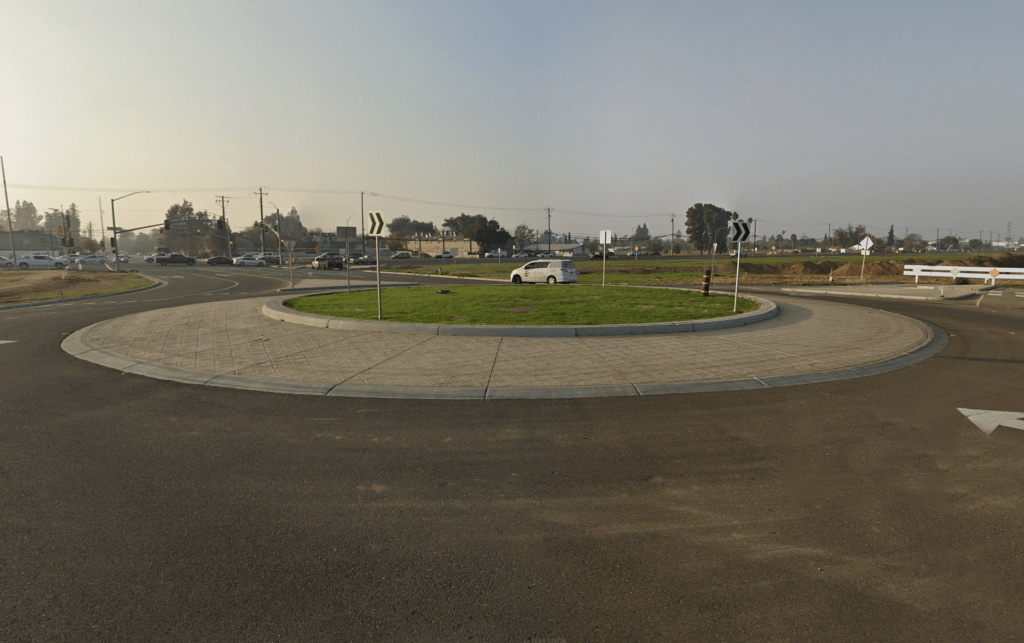 Des traces de pneus sont visibles sur l'herbe d'un rond-point, indiquant qu'une voiture a traversé tout droit au lieu de suivre la voie circulaire.