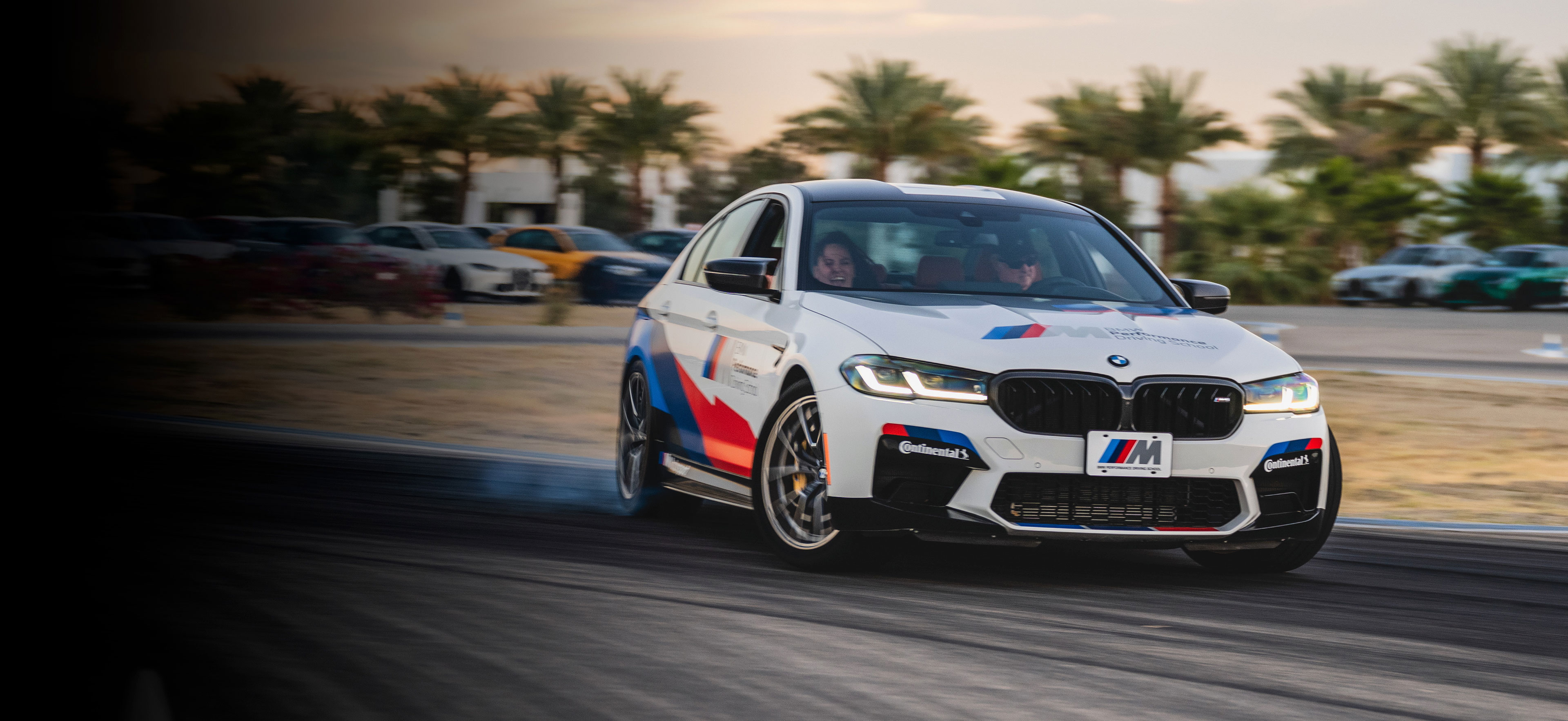 Une BMW Série M électrique bleue foncée roule à grande vitesse sur un circuit, avec un arrière-plan flou suggérant le mouvement.