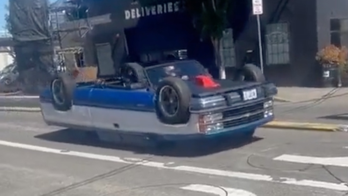 Des personnes regardant avec surprise une vidéo d'une voiture roulant tête en bas sur un écran.